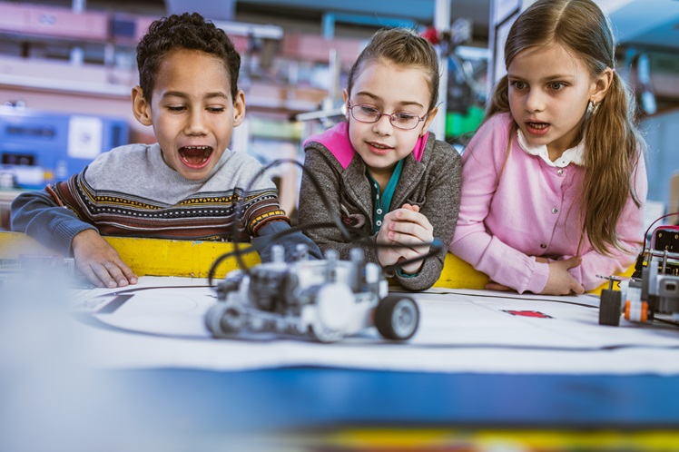 Group of surprised kids looking at futuristic robot they have made in laboratory.