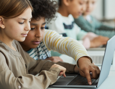 Two children working together on a budget-friendly laptop, perfect for elementary and middle school virtual learning needs.