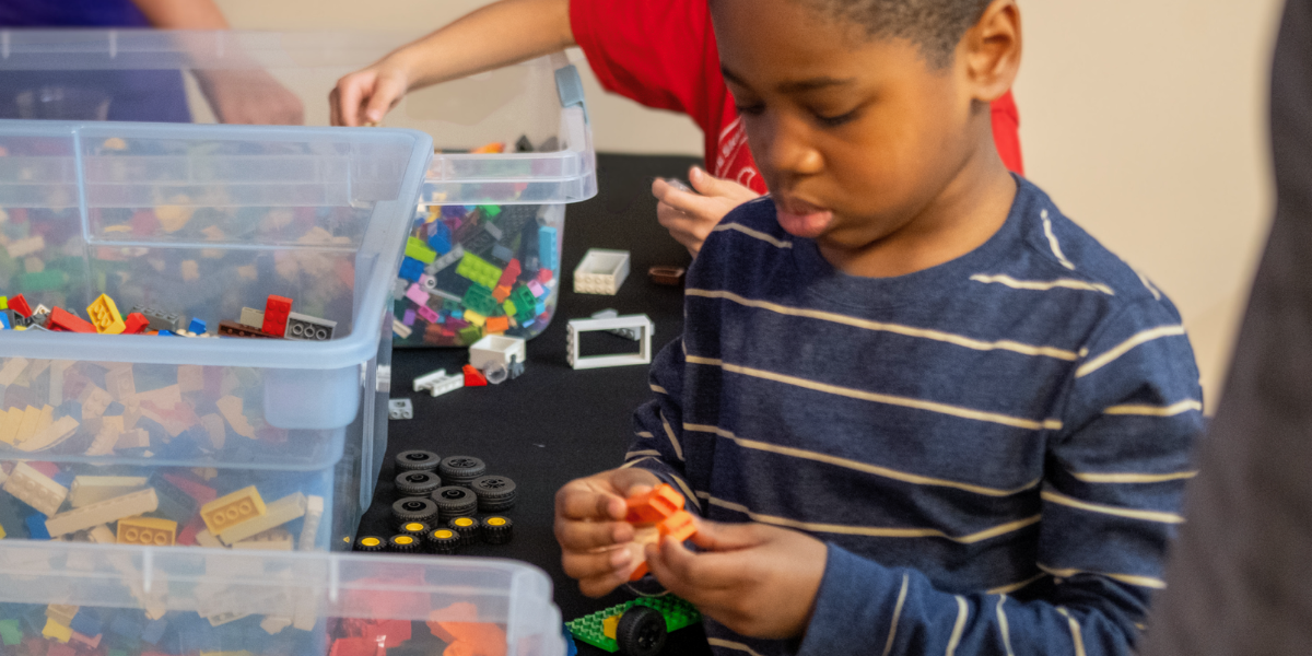 Child engaged in LEGO construction during an Engineering For Kids<sup srcset=